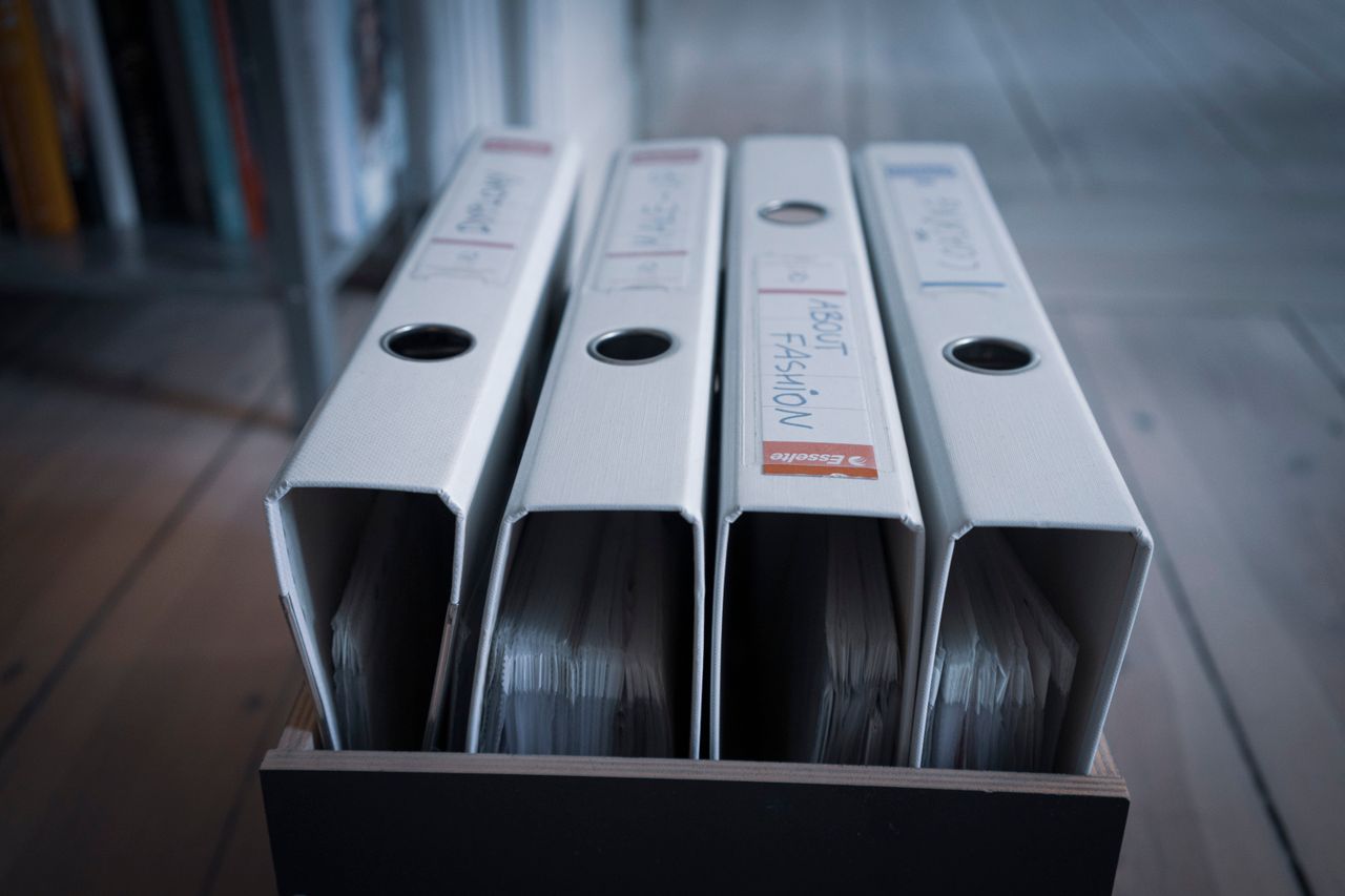 From above of similar folders with plastic sleeves and titles on surface in wooden box on floor
