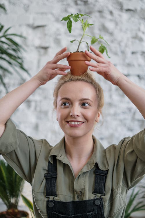 Smiling Woman in Green Button Up Shirt Holding Brown Pot