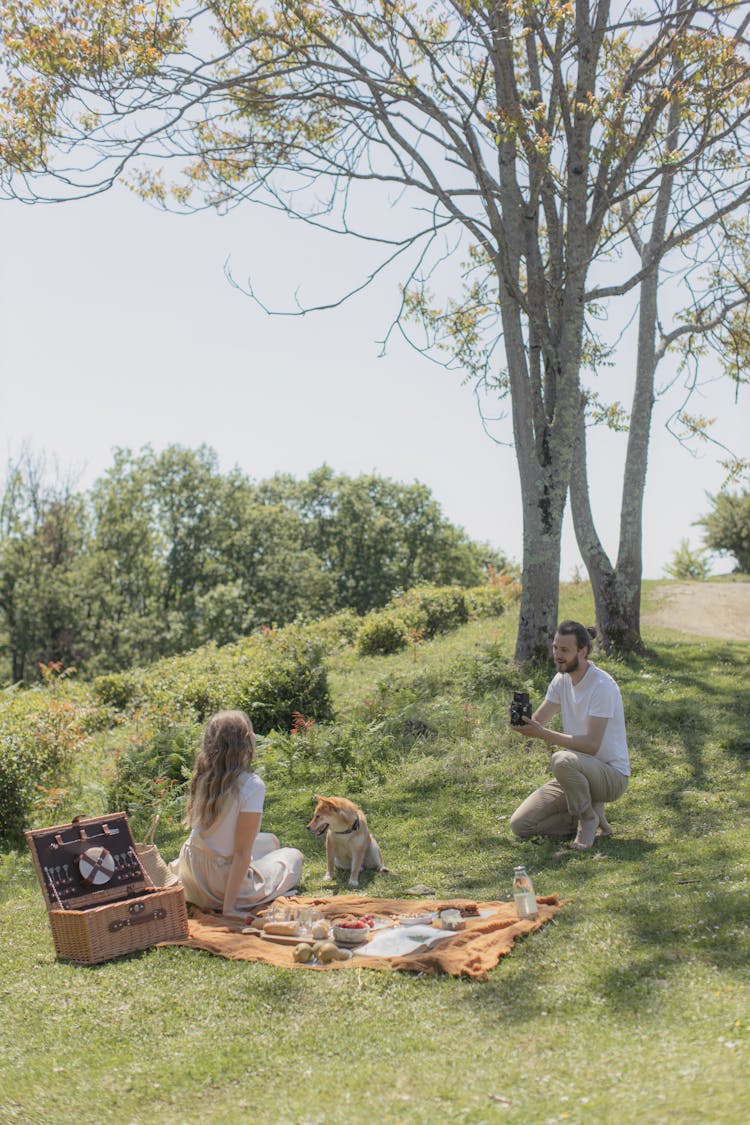 Man Sitting Taking A Photo Of A Woman And A Dog