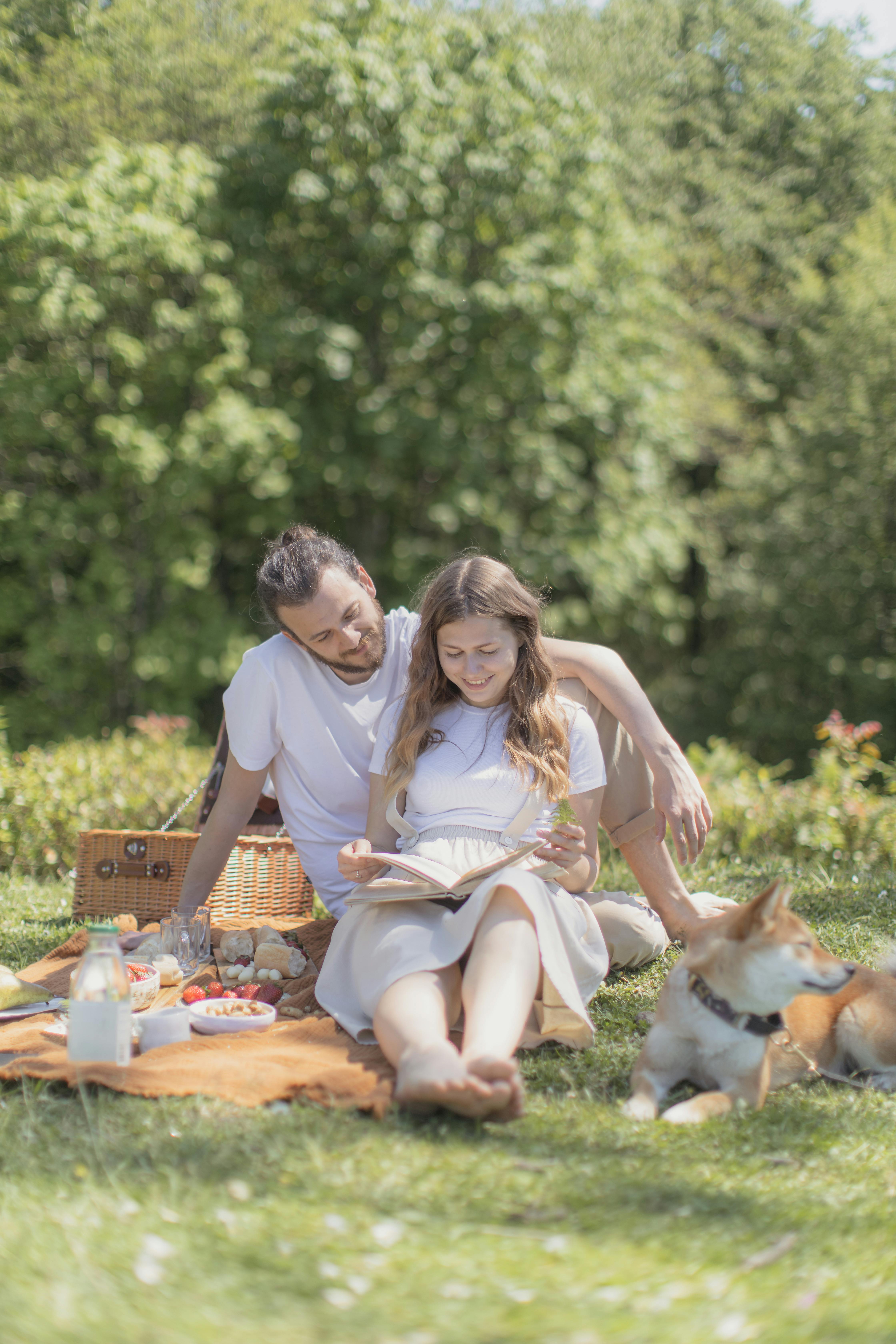 man and woman sitting on picnic mat with a dog