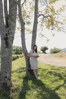 一位女士喜欢在阳光明媚的公园里，悠闲地坐在树下读书