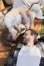 阳光明媚的日子里，一对年轻夫妇拥抱着他们的柴犬，躺在户外的毯子上