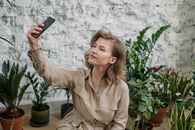 一位年轻女子在自家花园里，被各种室内植物环绕着自拍，捕捉这一瞬间