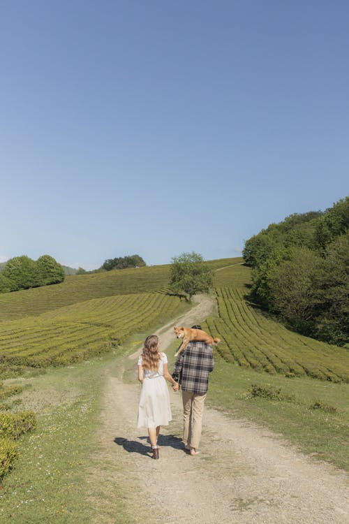 Free Lovely Couple Walking on Pathway With A Dog On The Man's Back Stock Photo
