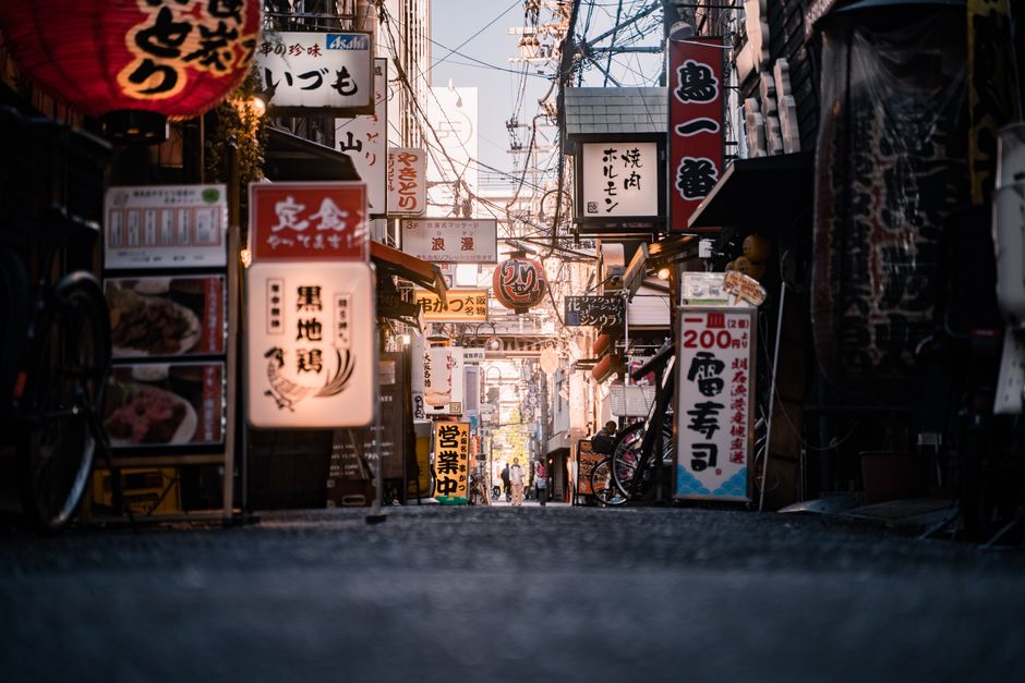 ネオン看板と店舗が並ぶ大阪の道頓堀の賑やかな通り。活気ある都市生活を捉えています。