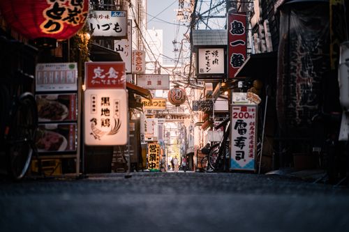 Free Bustling street in Dotonbori Osaka with neon signs and shops, capturing vibrant urban life. Stock Photo