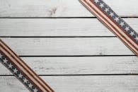 From above of similar ornamental ribbons with stripes and stars representing   patriotism on wooden surface