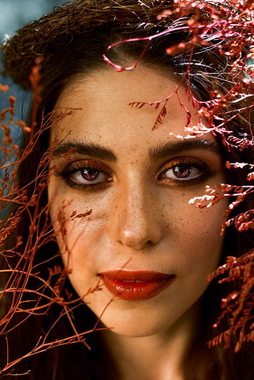 Free Close-up Photo of a Woman's Face near Leaves Stock Photo