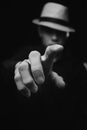 Black and white of unrecognizable male in stylish straw hat standing with reached arm and finger on black background