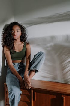 一位卷发的年轻女子坐在家具上，沐浴在光影中