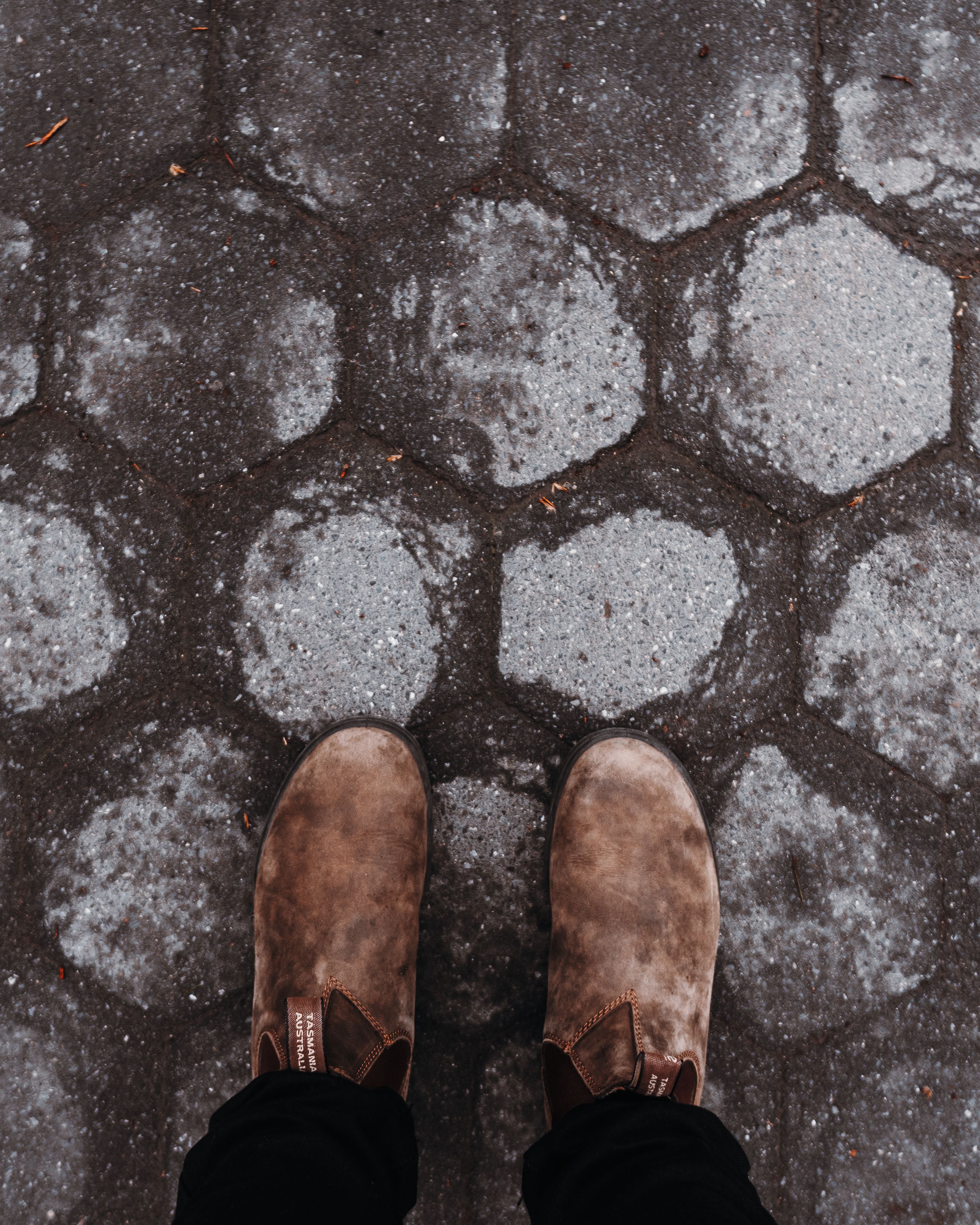 Top view of brown shoes on a hexagonal concrete pattern pavement.