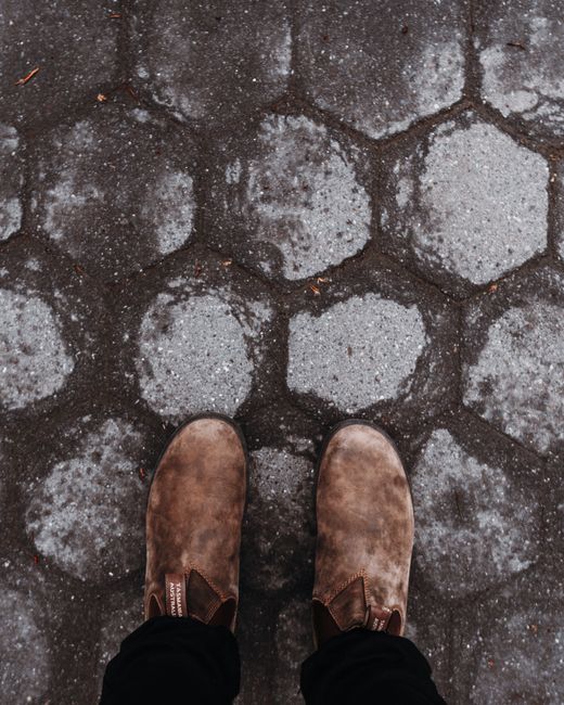 Top view of brown shoes on a hexagonal concrete pattern pavement.
