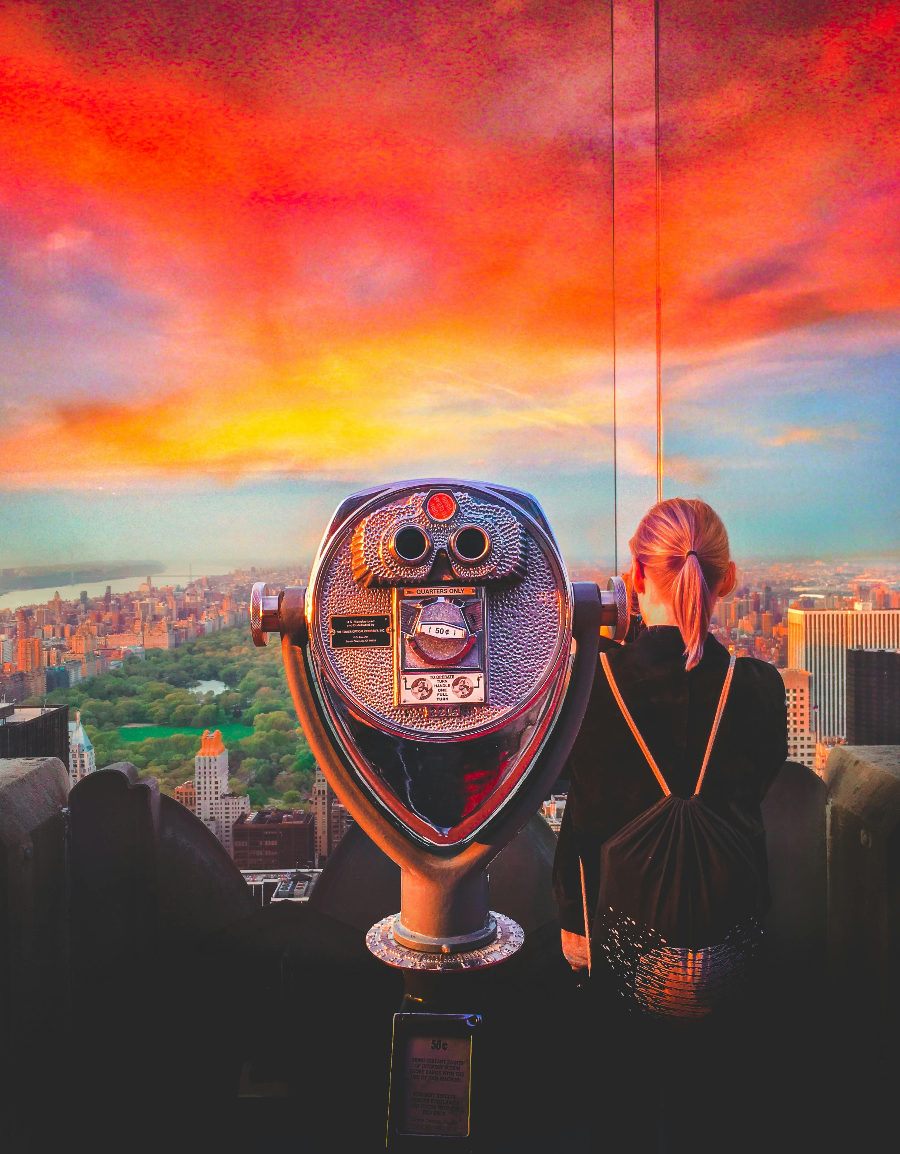 woman standing beside silver coin operated scope