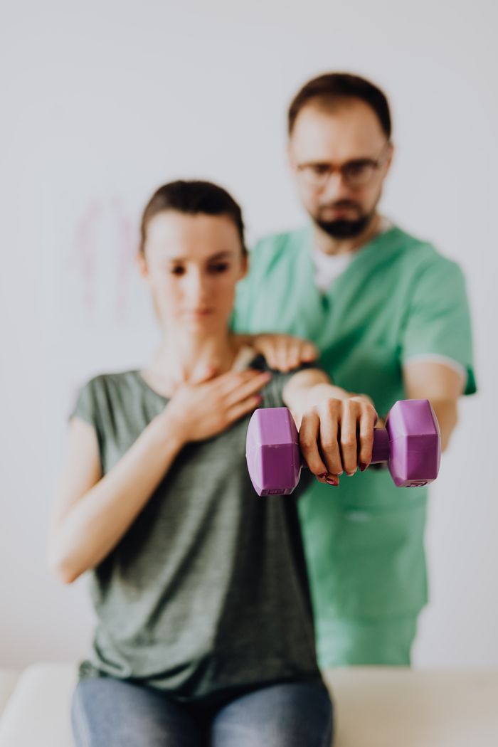Chiropractor assisting patient in treatment room