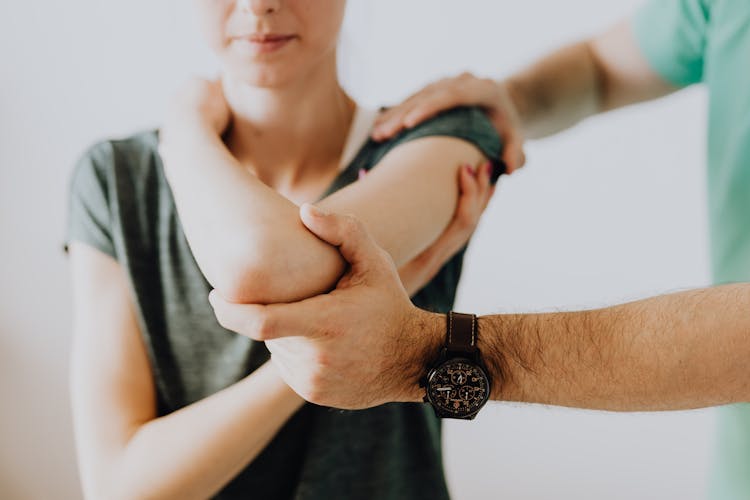 Crop Unrecognizable Chiropractor Examining Arm Joint Of Female Patient