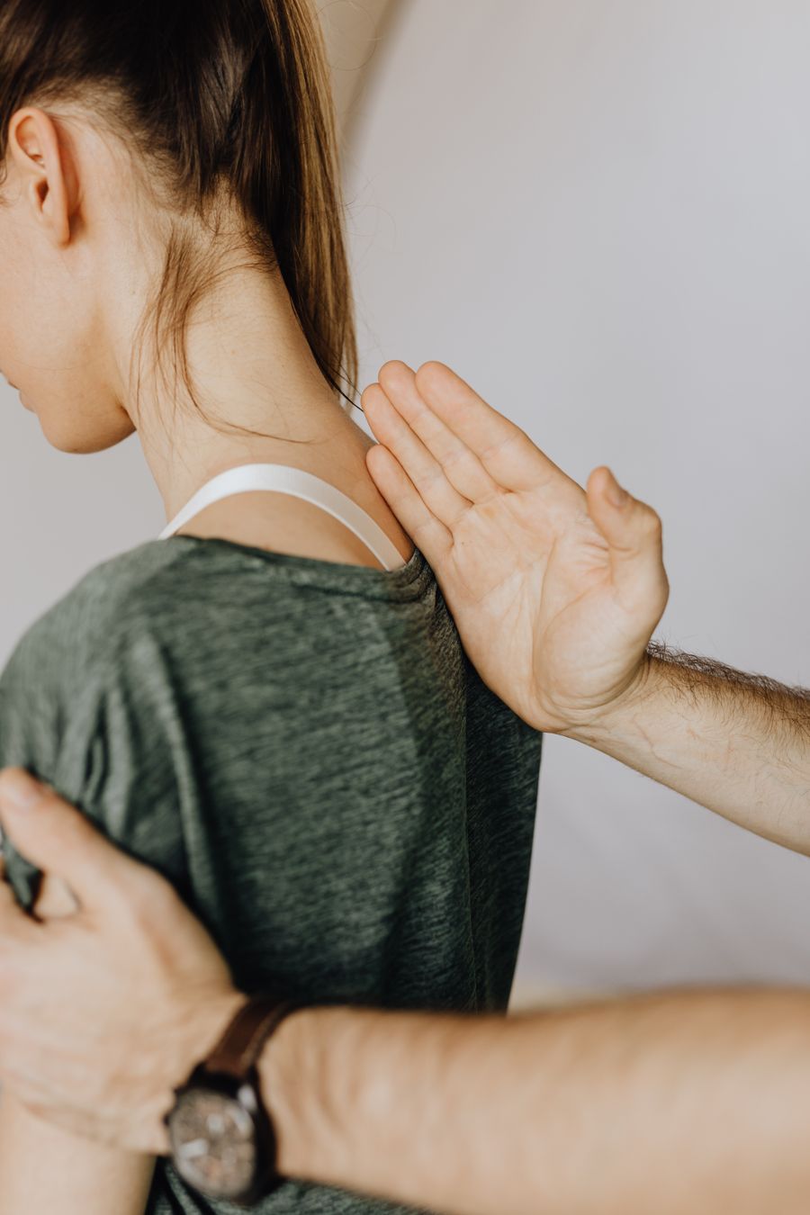 Main posée à plat entre l'omoplate et les cervicales d'une patiente, lors d'un test de palpation.