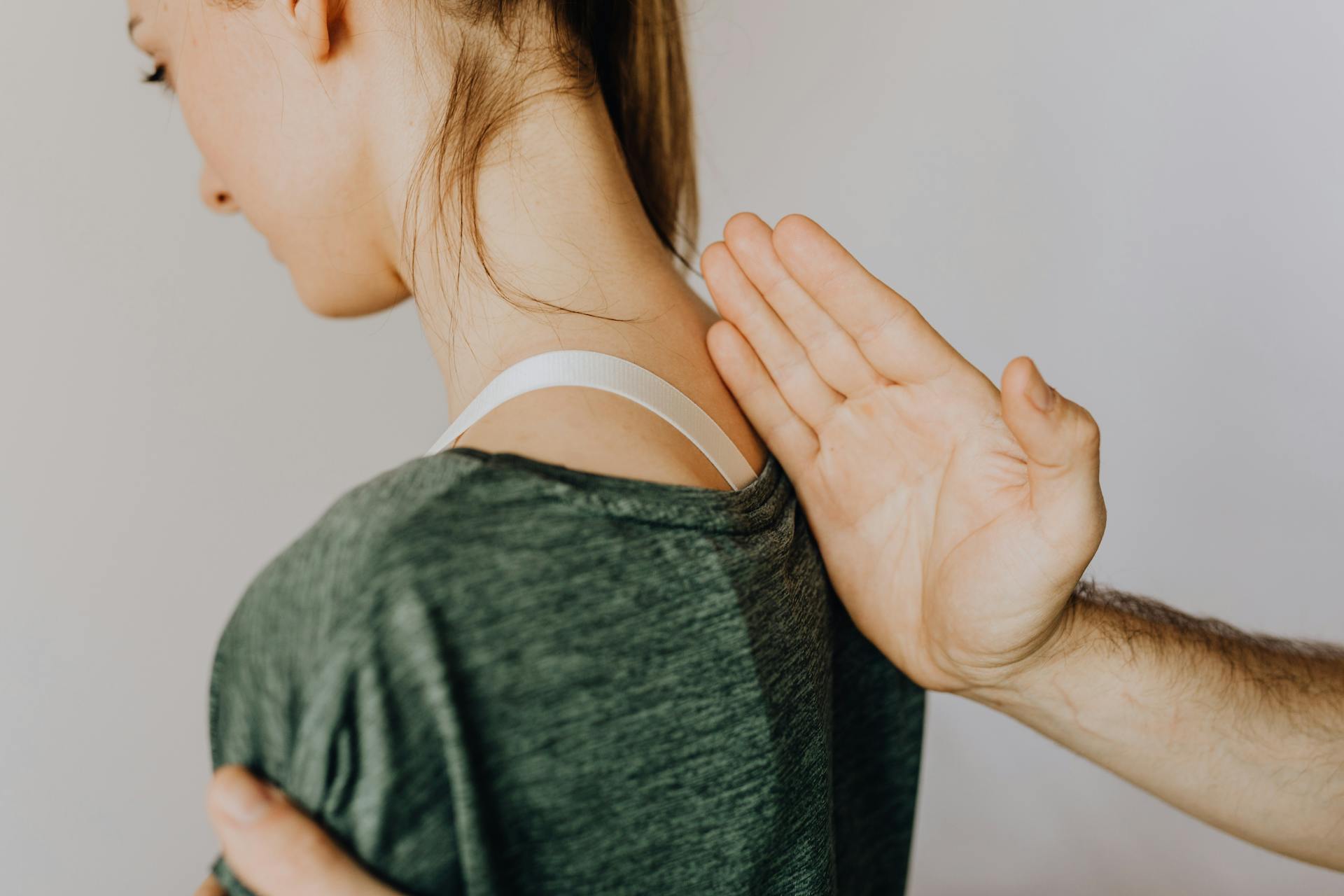 Crop unrecognizable orthopedist checking up back of woman in clinic