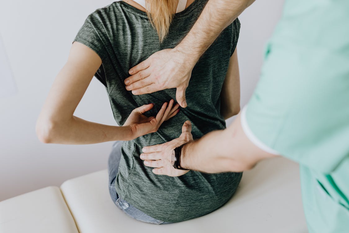 Crop unrecognizable woman showing chiropractor painful spot on back