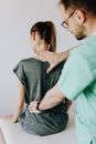 医生在诊所给坐着的患者检查脊柱