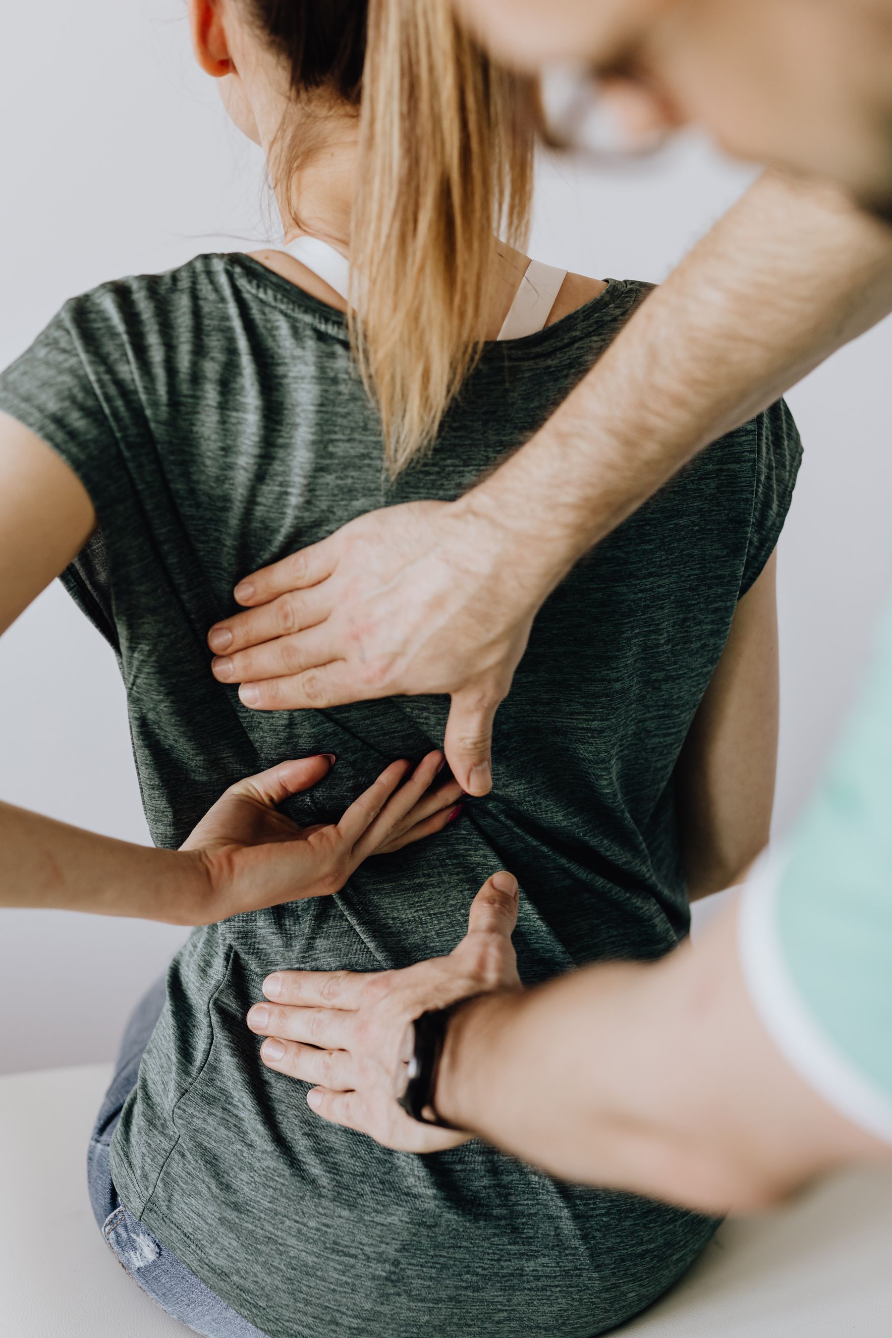 A chiropractor examining a patient's back in a bright clinical treatment room