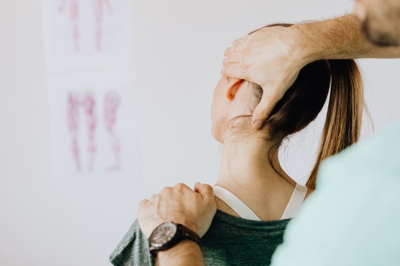 Clinician assessing the upper cervical spine of a patient in a clinical setting