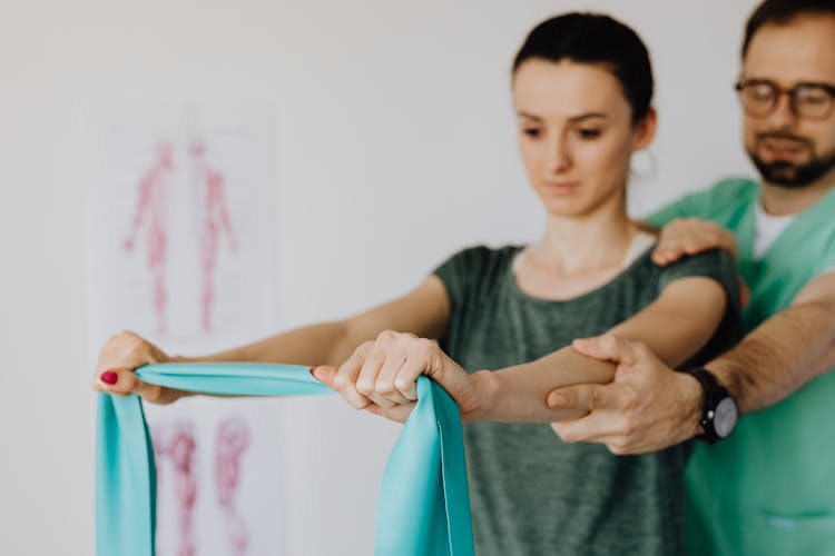 Crop Orthopedist Checking Up Female Patient With Elastic Band