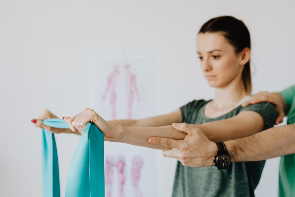 Slim young female in casual wear standing with reached arms and elastic tape during medical checkup by crop unrecognizable osteopath in wristwatch