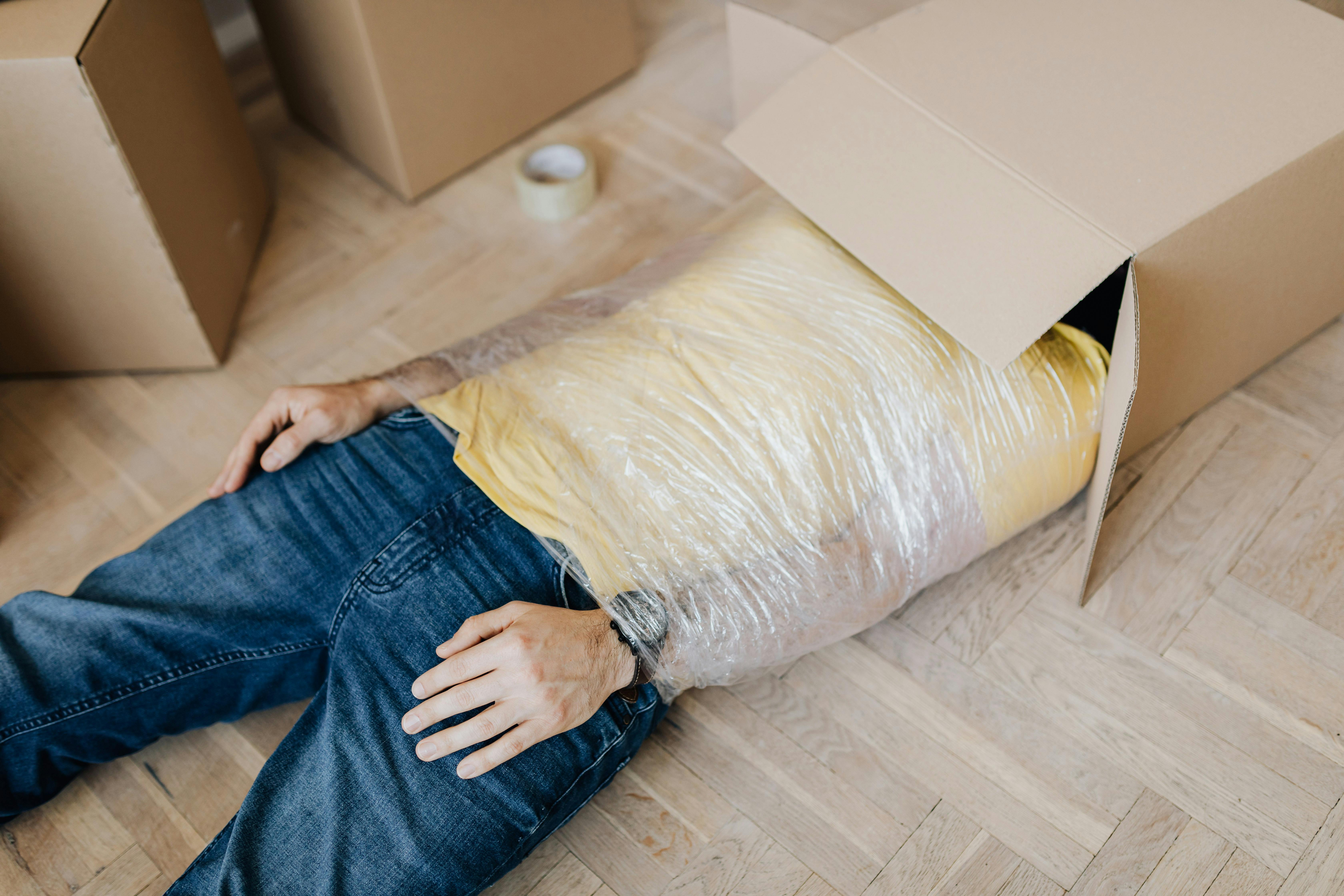 man tied up using tape with head in carton box