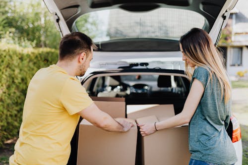 Calm couple putting carton boxes into car trunk