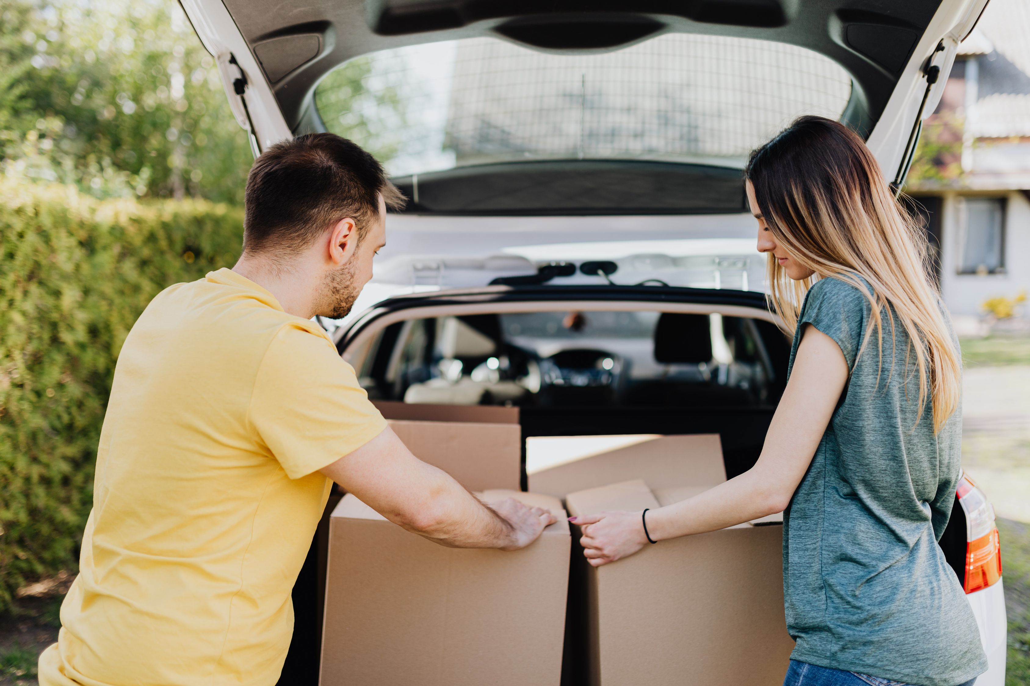 Calm couple putting carton boxes into car trunk · Free Stock Photo