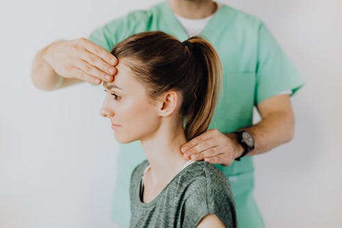 Free Professional massage therapist performing head and neck massage on content female patient relieving sore neck tensions Stock Photo