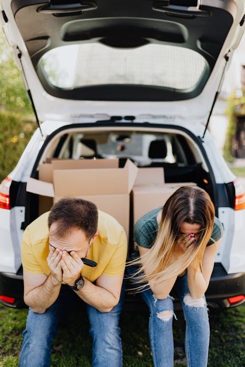 Free Tired couple sitting on car luggage boot Stock Photo