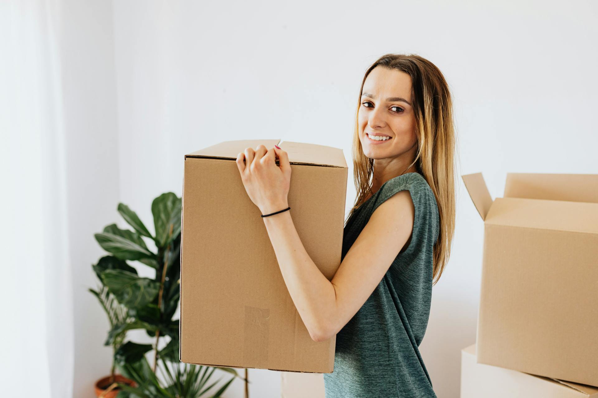 Cheerful woman carrying packed carton box