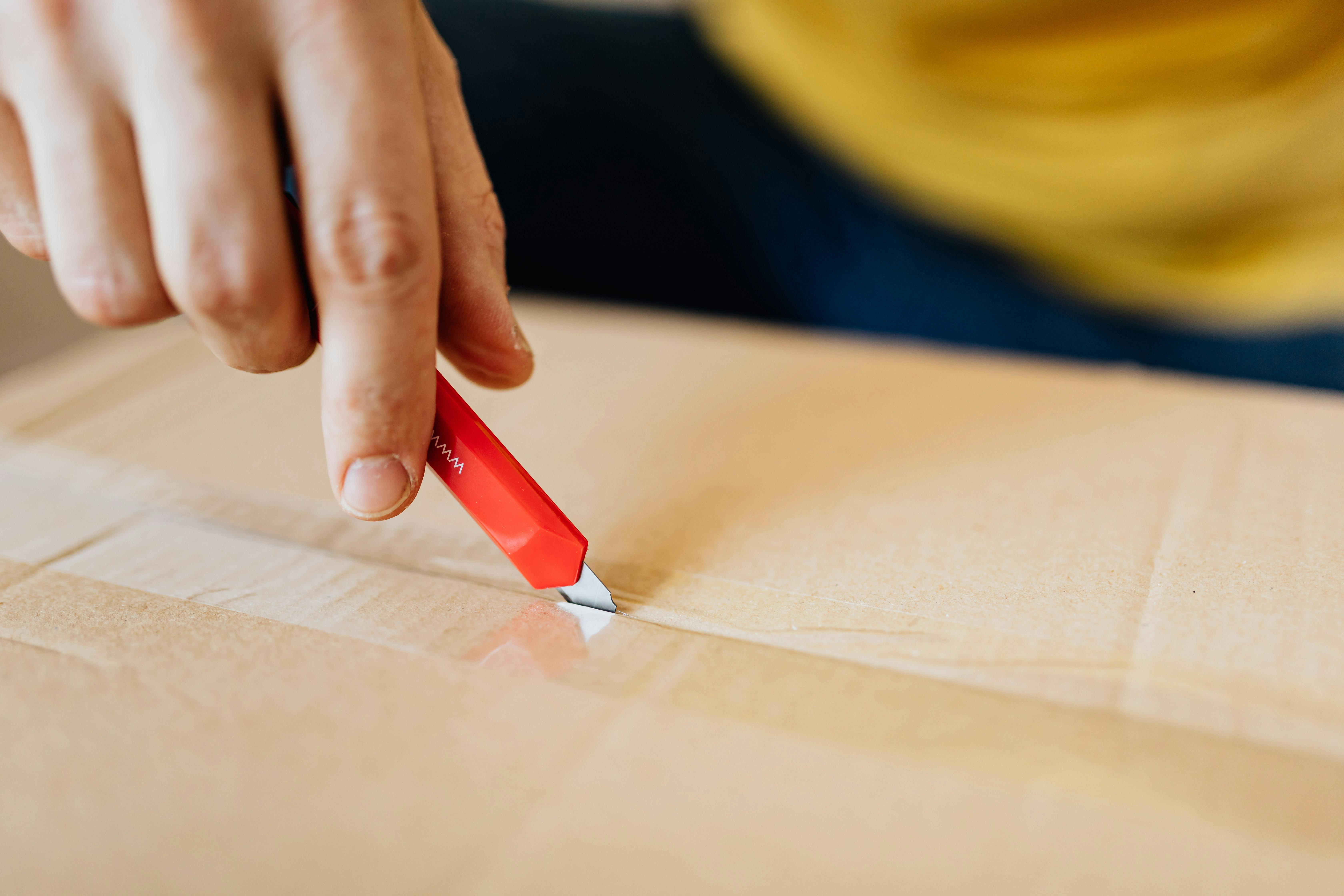 crop man cutting tape on carton box