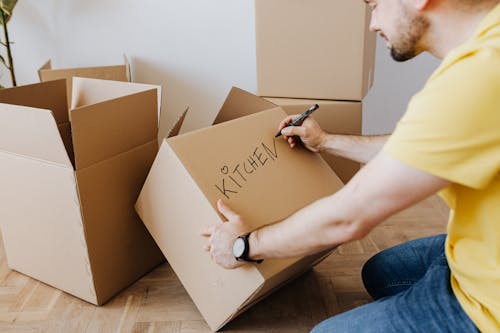 Crop man with pile of cardboard boxes for packing belongings