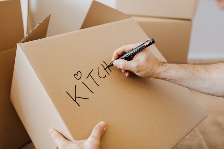 Crop Man Signing Carton Moving Boxes