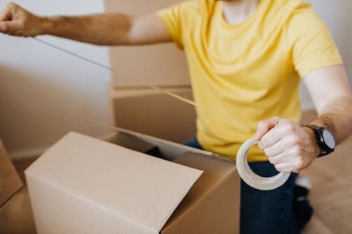 Crop man with cardboard boxes while packing belongings