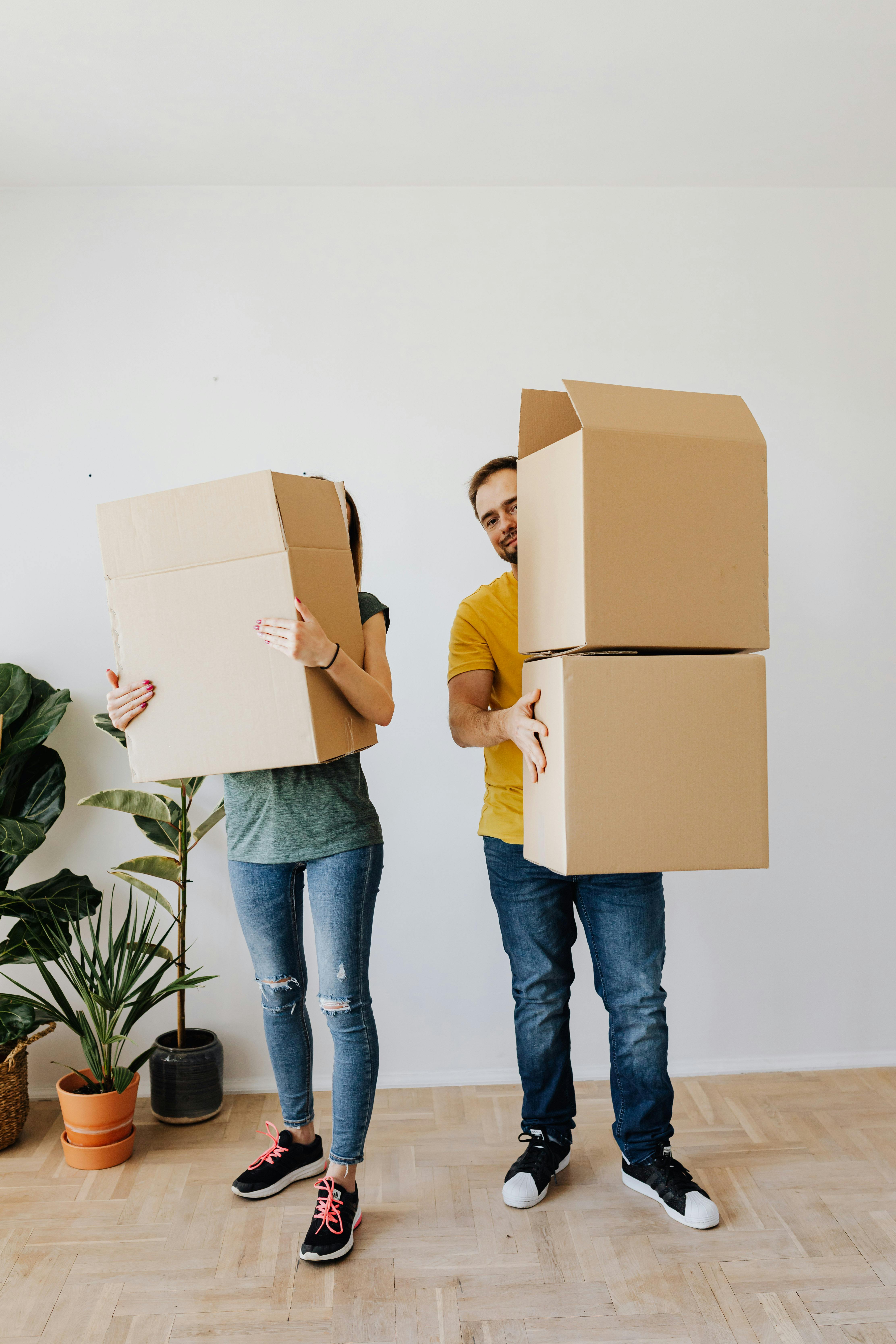 relocating couple carrying carton boxes in new apartment