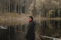 一位妇女站在立陶宛一个平静的湖边，周围是宁静的森林