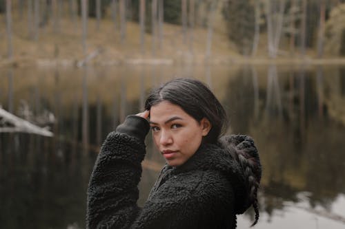 Portrait of a Woman in a Black Hoodie Near a Lake
