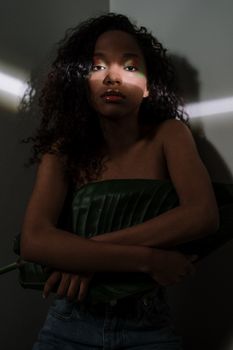 一位卷发妇女手持一片大叶子，在戏剧性的灯光下拍摄的艺术肖像