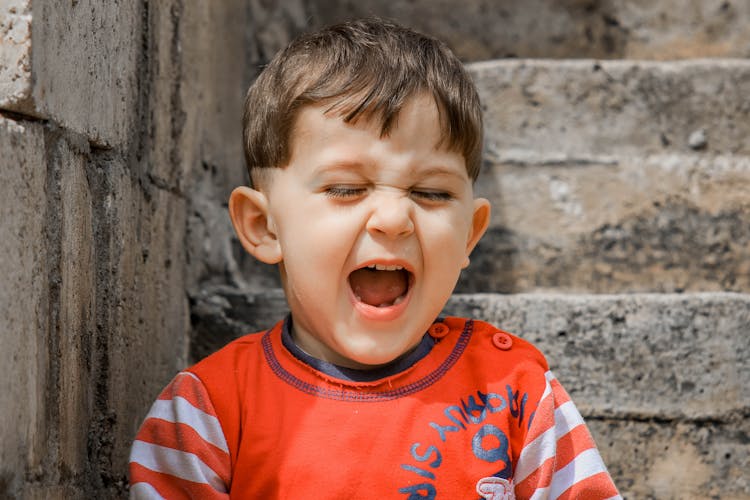 Little Child Shouting Near Shabby Walls On Street