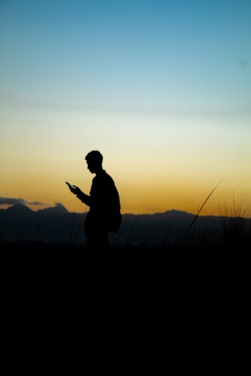 Free Silhouette of a Person Standing during Sunset Stock Photo