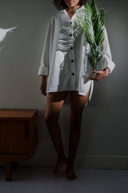 Woman in Gray Coat Standing Beside White Wall