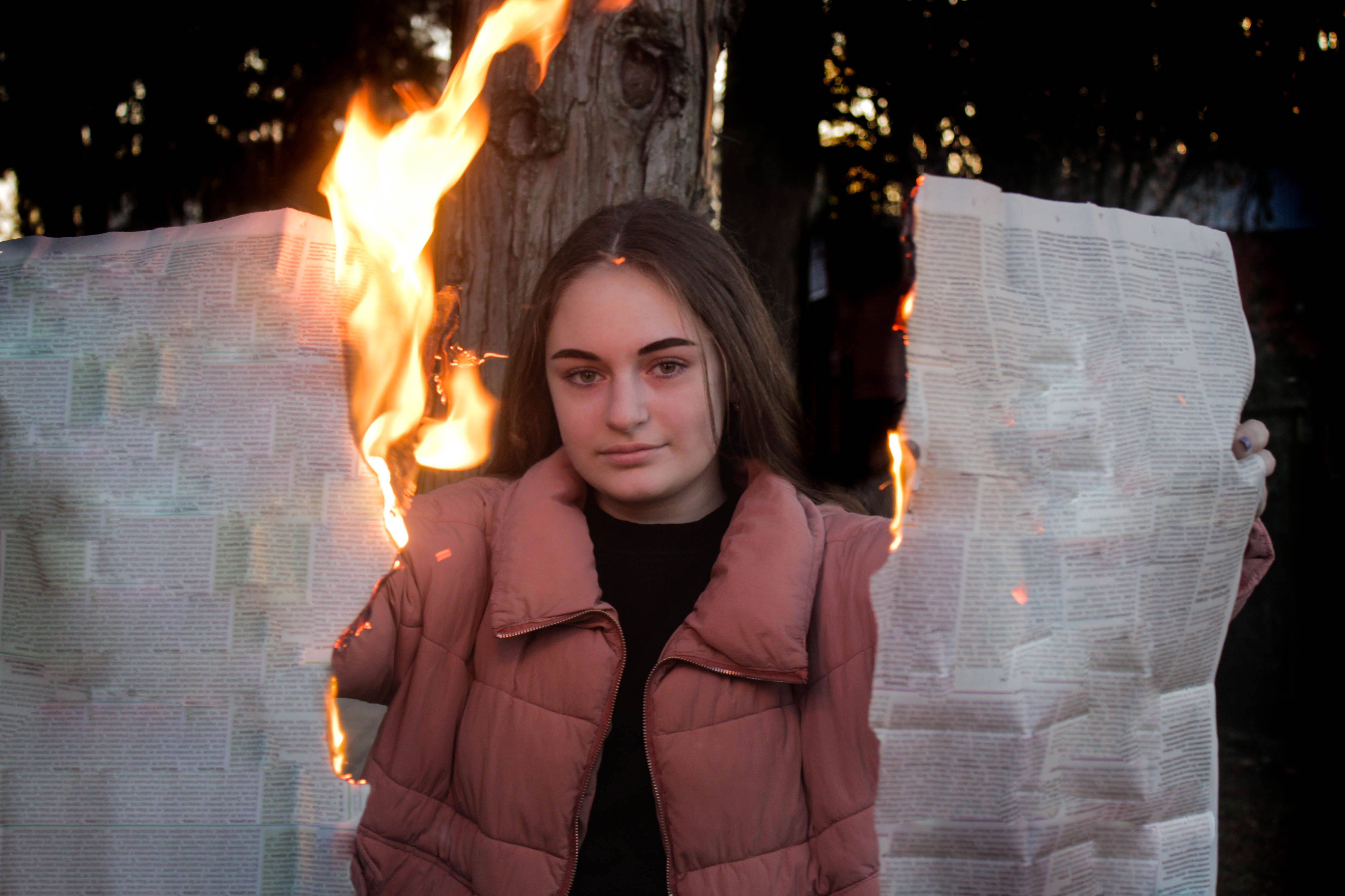 Woman burning newspaper in bright fire near tree · Free Stock Photo