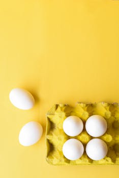Top view of white eggs on a yellow background, perfect for food photography and lifestyle content.