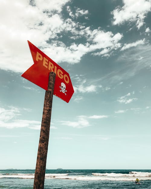 Low angle of sign located near sea water waving under blue sky in summer sunny day