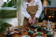 一名系着围裙的妇女正用园艺工具组装一个美丽的室内多肉植物玻璃器皿
