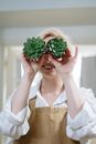 一位开朗的女人在室内拿着多肉植物当眼镜玩乐