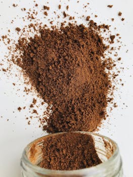 Close-up of aromatic ground coffee spilled from a jar on a white background.